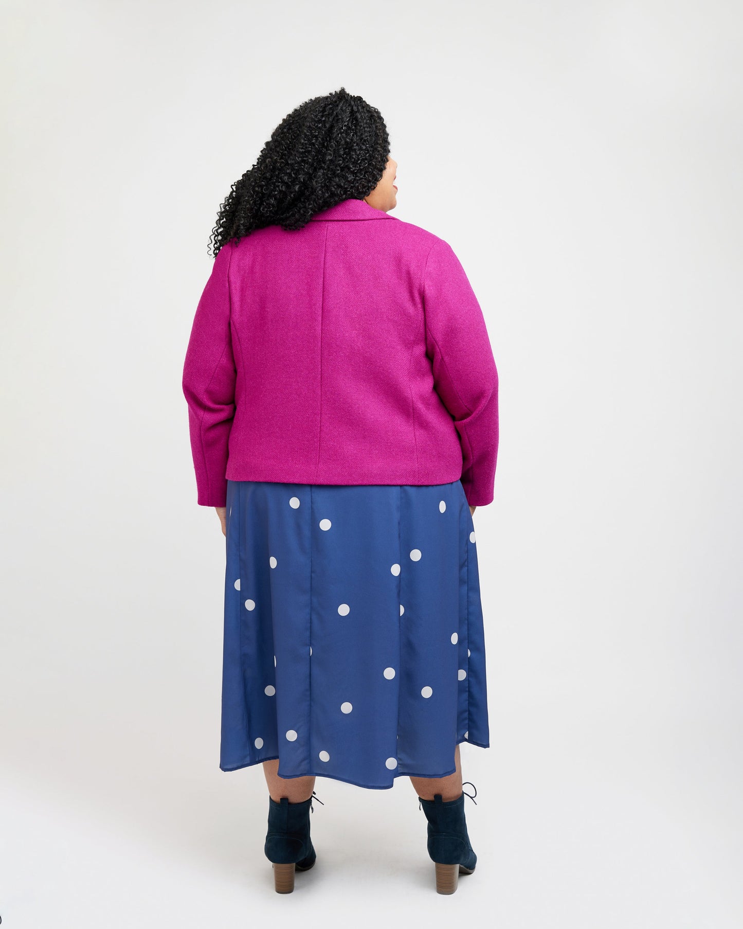 Person wearing a pink jacket and blue polka dot dress on a white background. This blazer is the Auburn Blazer sewing pattern from Cashmerette.