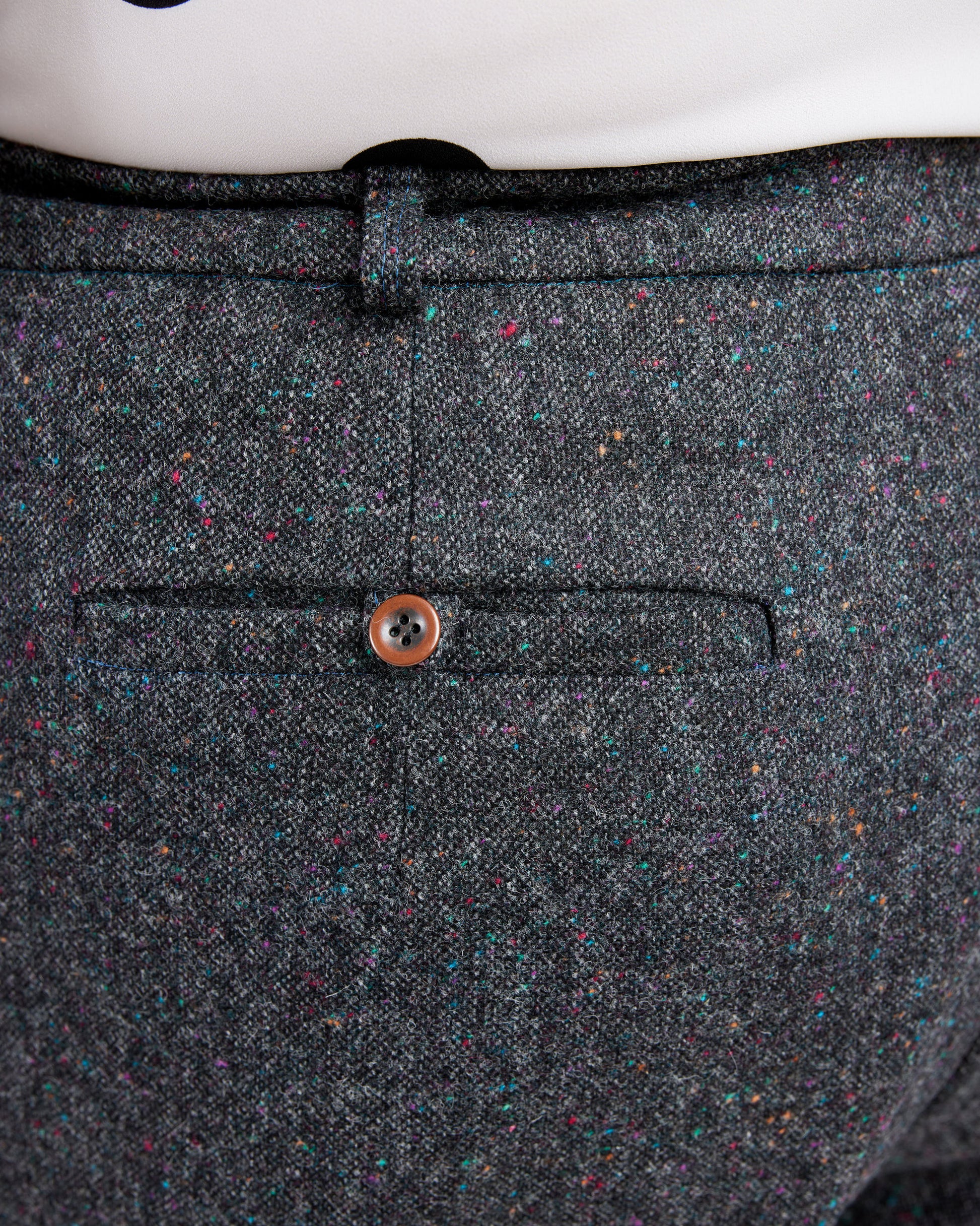 Close-up of a gray textured fabric with a button on a white background. These pants are the Meriam Trousers sewing pattern from Cashmerette.