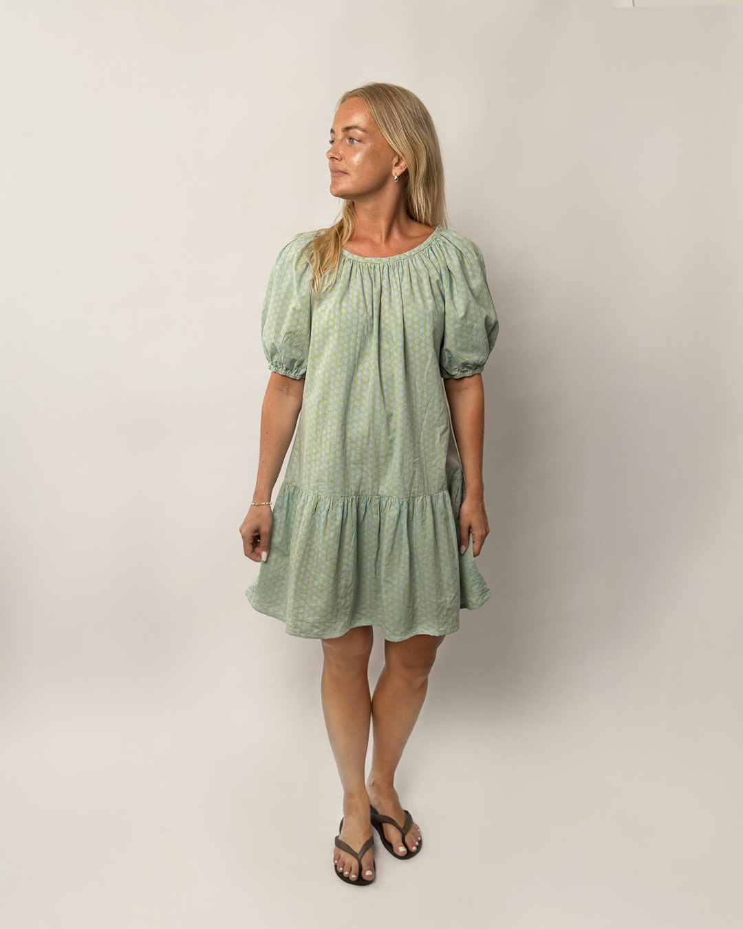 Woman wearing a green dress with puff sleeves against a plain background