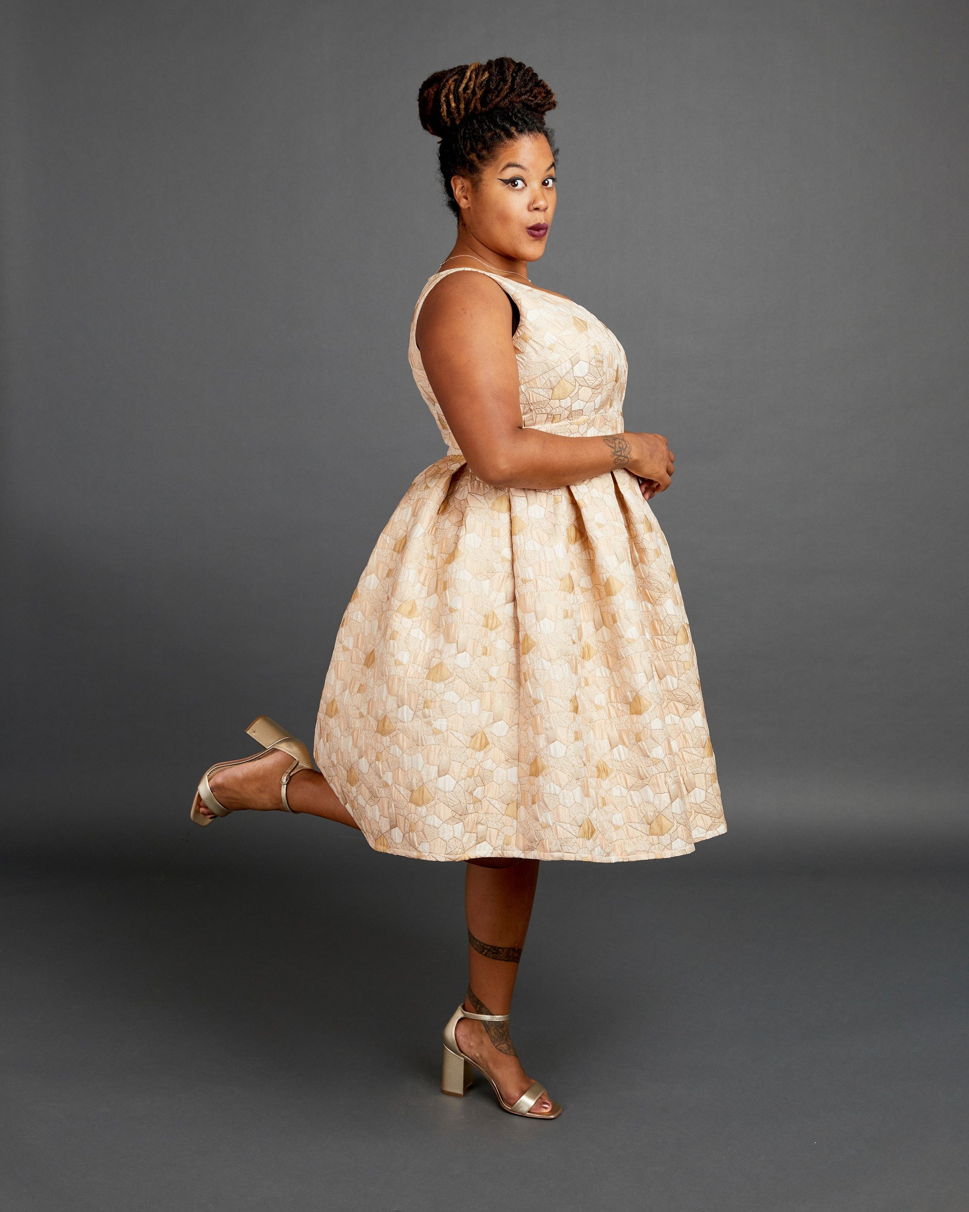 Woman wearing a beige patterned dress against a gray background. This dress is the Upton Dress & Skirt sewing pattern from Cashmerette.
