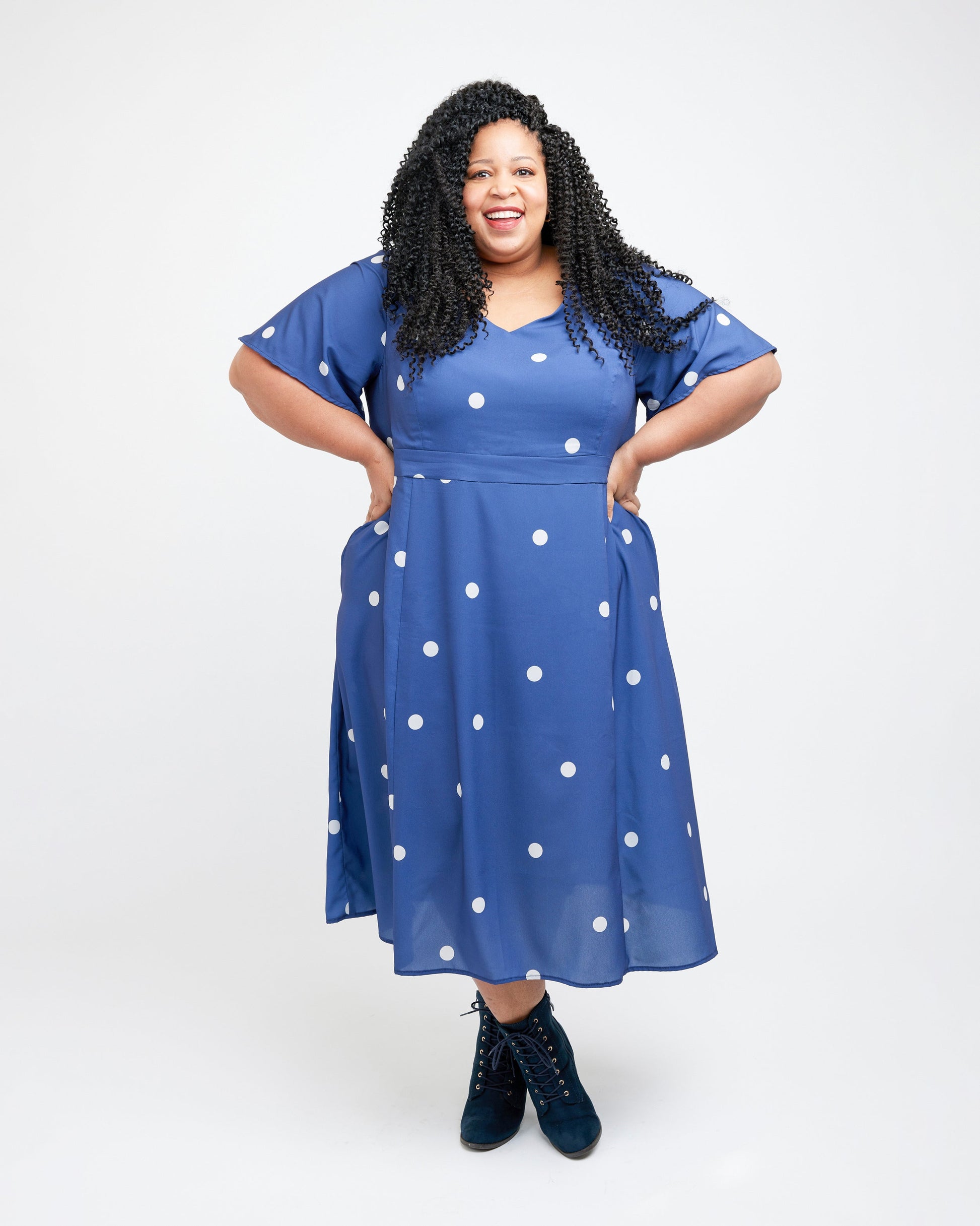 Woman wearing a blue dress with white polka dots on a white background. This dress is the Upton Dress & Skirt sewing pattern from Cashmerette.