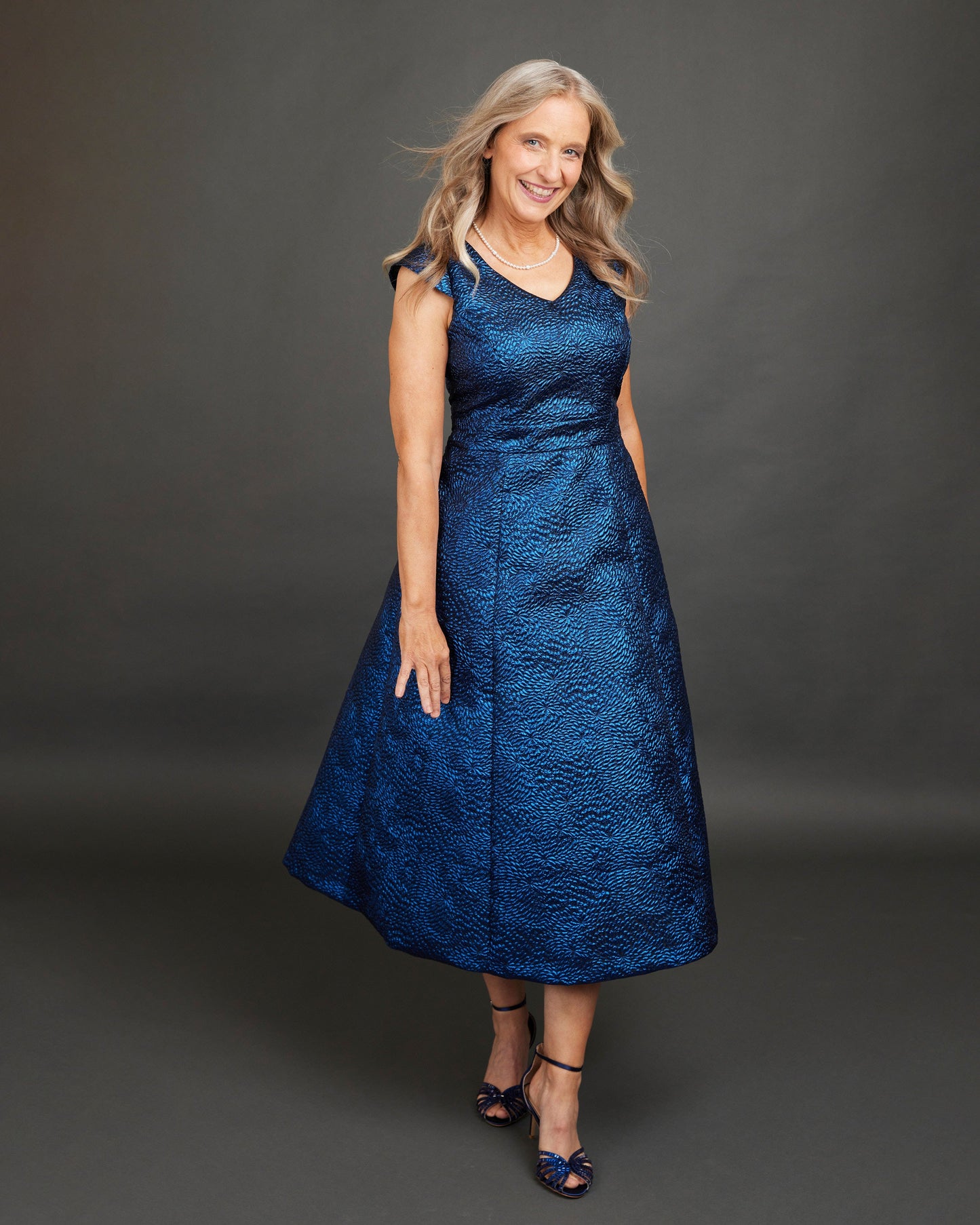 Woman wearing a blue dress against a gray background. This dress is the Upton Dress & Skirt sewing pattern from Cashmerette.