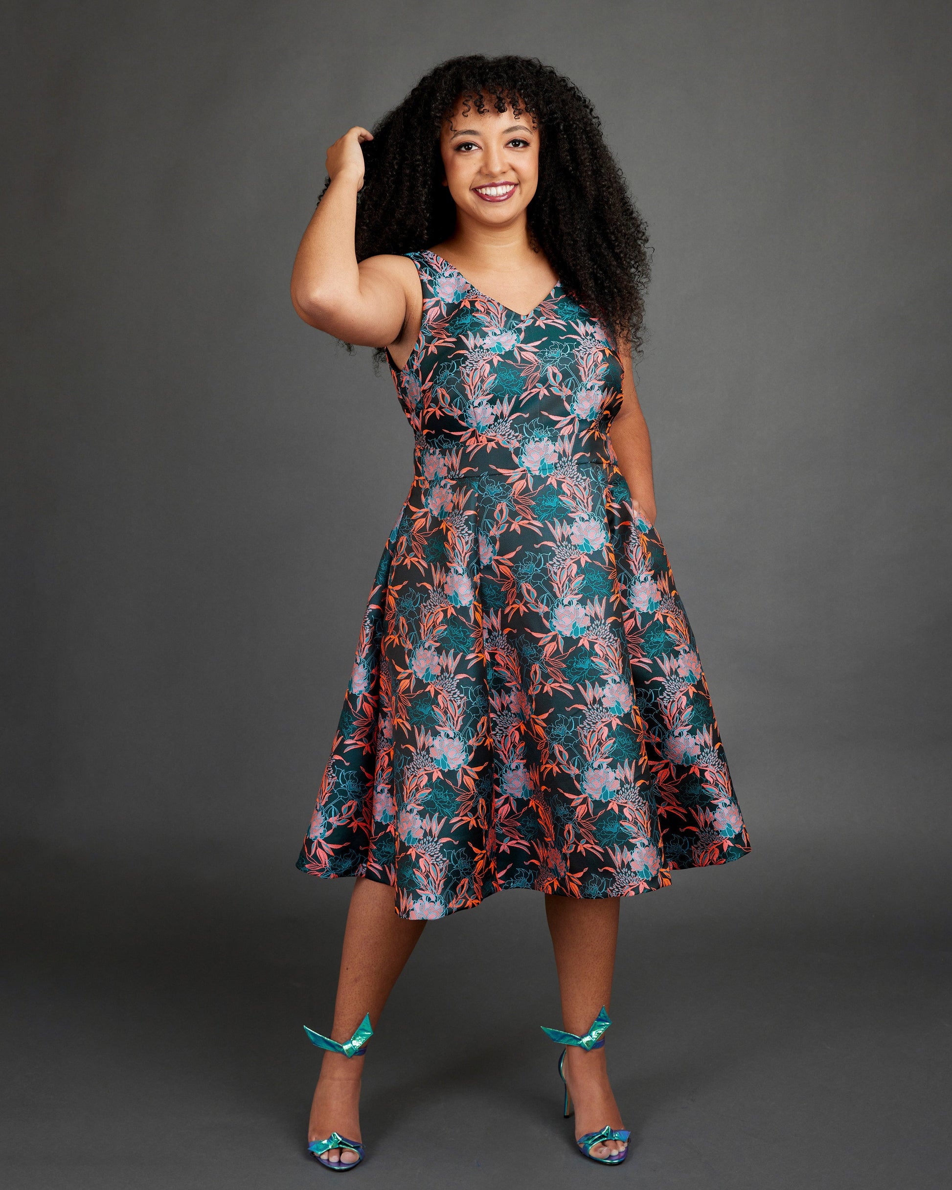 Woman wearing a floral dress against a gray background. This dress is the Upton Dress & Skirt sewing pattern from Cashmerette.