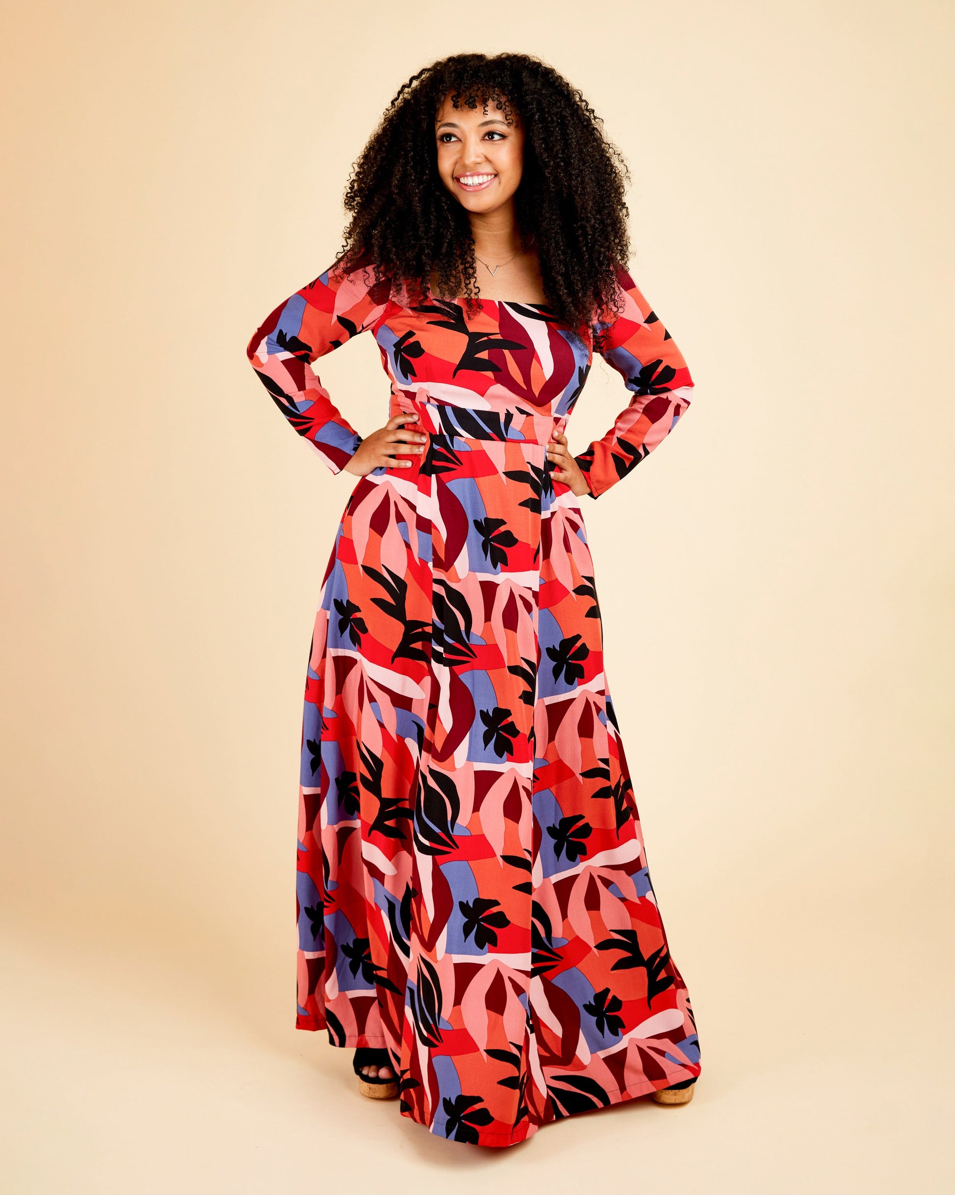 Woman wearing a colorful patterned dress on a beige background. This dress is the Upton Dress & Skirt sewing pattern from Cashmerette.