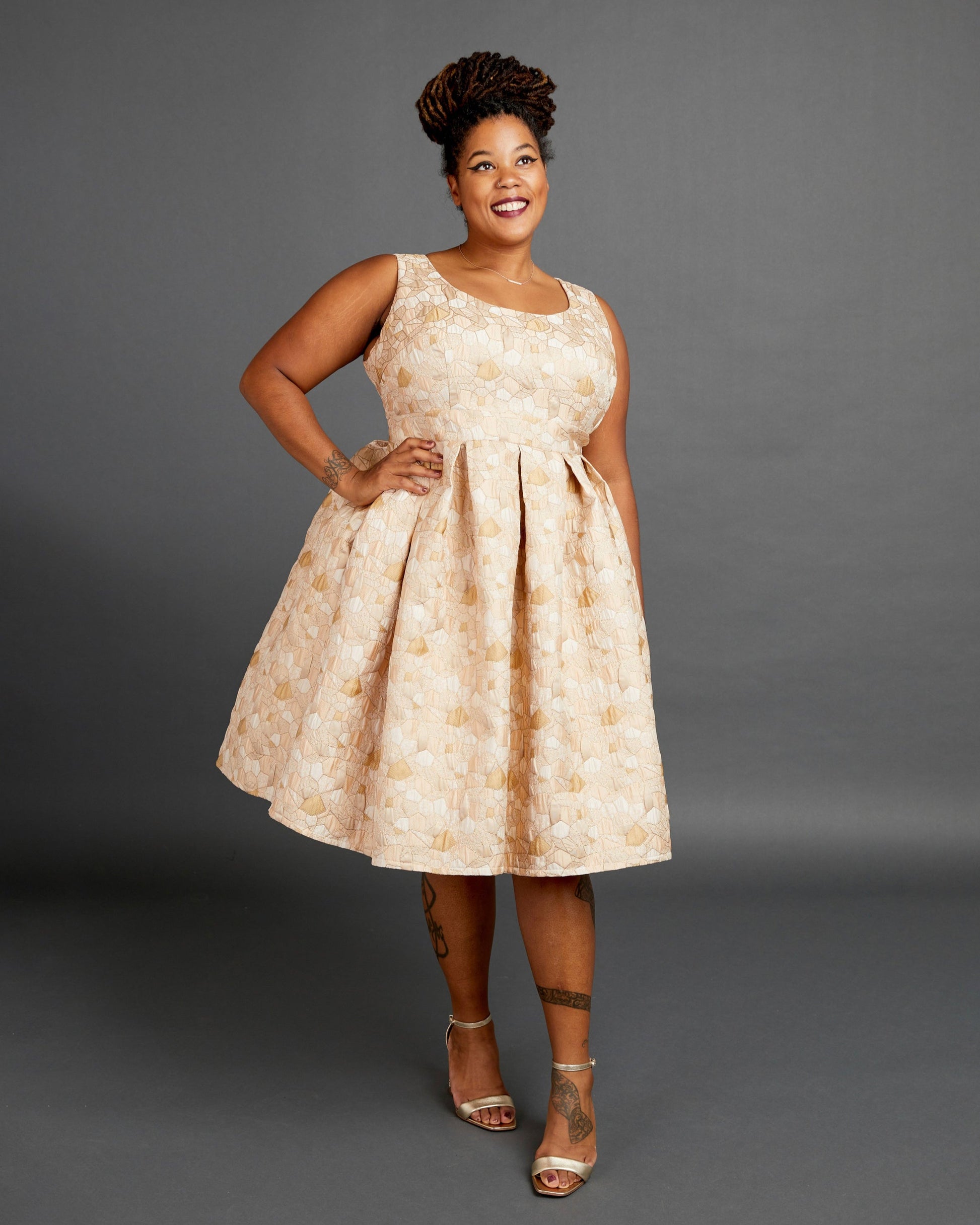 Woman wearing a beige floral dress against a gray background. This dress is the Upton Dress & Skirt sewing pattern from Cashmerette.